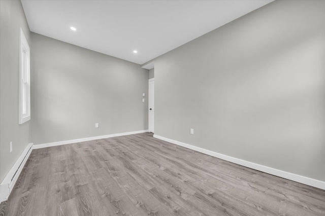 unfurnished room featuring a baseboard radiator, wood finished floors, baseboards, and recessed lighting