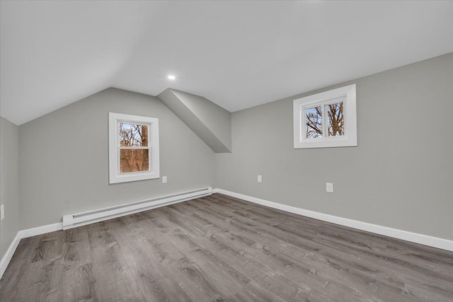 bonus room featuring baseboard heating, wood finished floors, baseboards, and a healthy amount of sunlight
