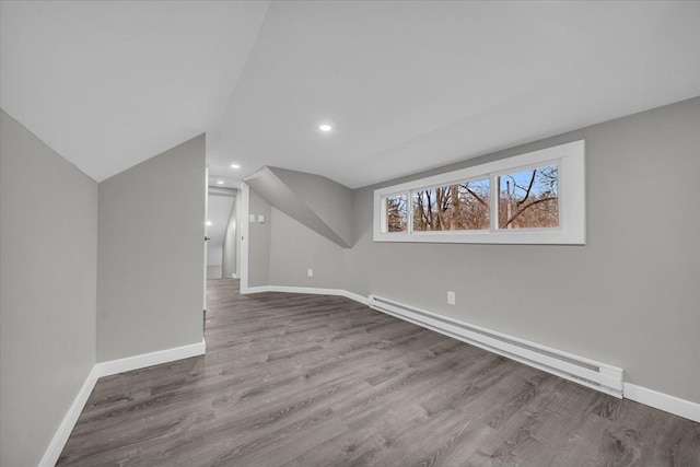 additional living space featuring baseboards, a baseboard heating unit, wood finished floors, and lofted ceiling