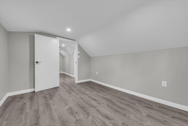 additional living space featuring wood finished floors, baseboards, vaulted ceiling, and recessed lighting