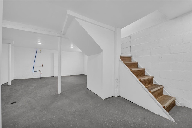 finished below grade area featuring concrete block wall and stairs