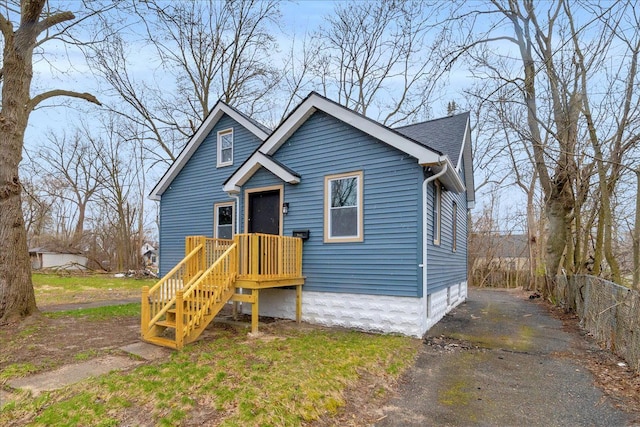bungalow-style house with aphalt driveway and fence