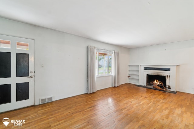 514 Chalmers St, Flint, MI 48503 - unfurnished living room with light wood finished floors and a brick fireplace