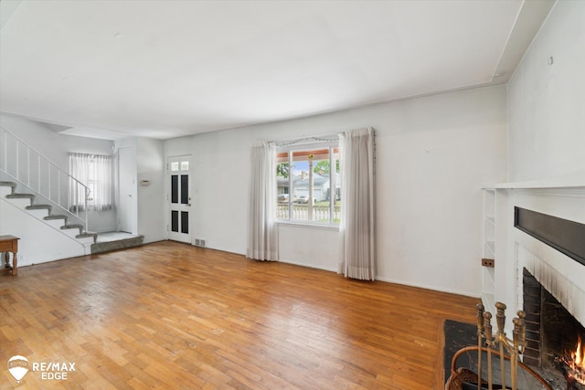 514 Chalmers St, Flint, MI 48503 - unfurnished living room with a fireplace, light wood-style floors, and stairs
