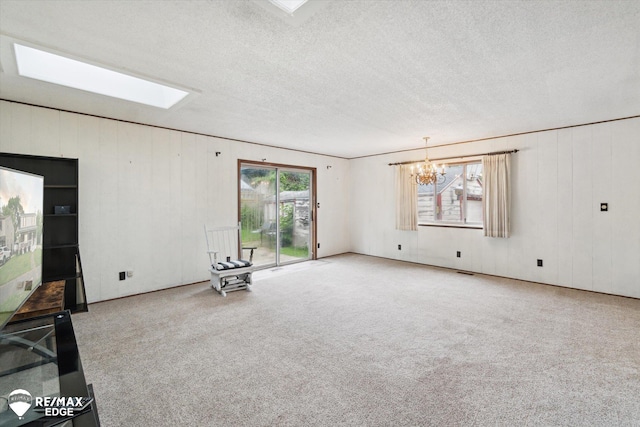 514 Chalmers St, Flint, MI 48503 - unfurnished living room featuring a chandelier, a skylight, carpet floors, a textured ceiling, and wood walls