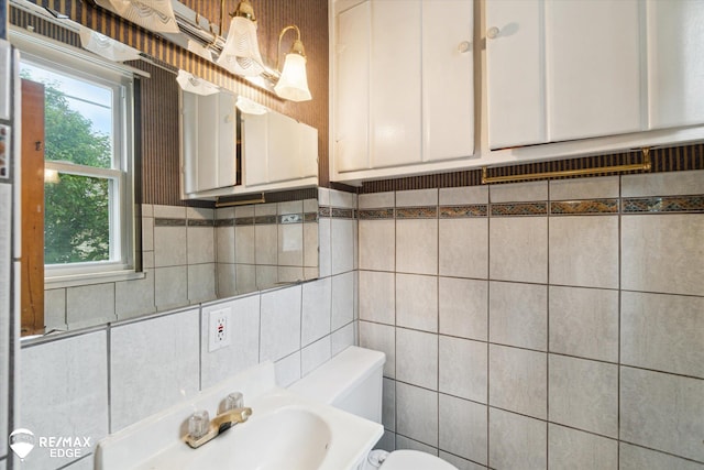514 Chalmers St, Flint, MI 48503 - bathroom featuring toilet, a sink, backsplash, and tile walls