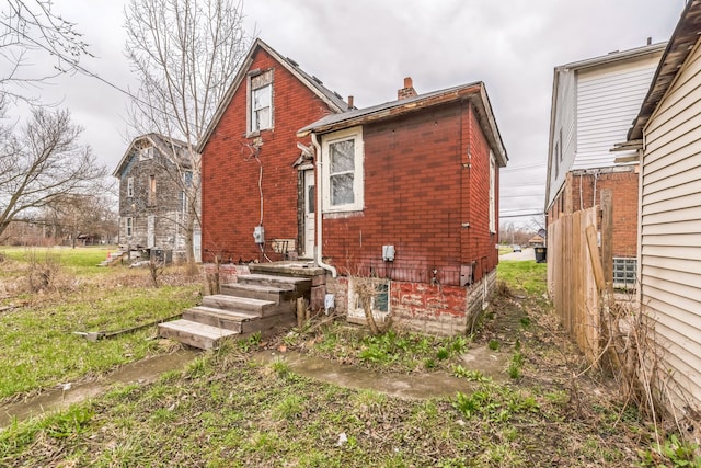 rear view of house with brick siding and a chimney