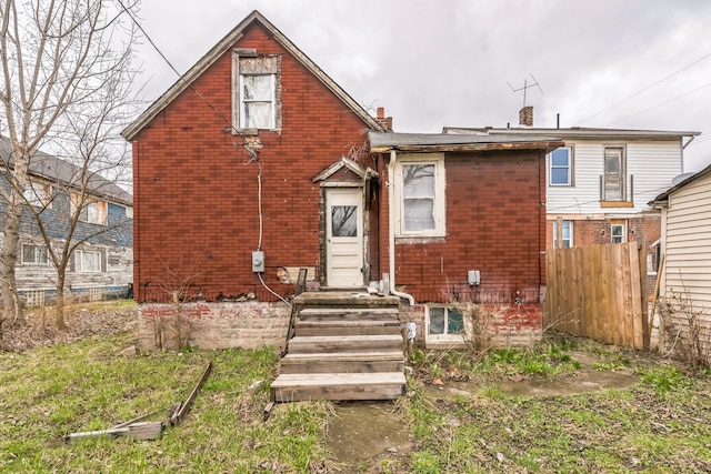 rear view of house with brick siding, fence, and a chimney