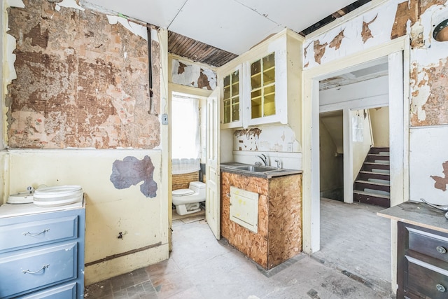 kitchen featuring a sink, glass insert cabinets, wainscoting, and blue cabinets