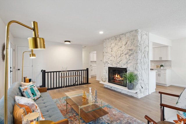 323 13th St, Plainwell, MI 49080 - living room featuring light wood finished floors, baseboards, a stone fireplace, and recessed lighting
