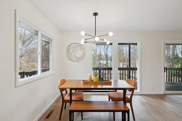 323 13th St, Plainwell, MI 49080 - dining room featuring wood finished floors, an inviting chandelier, baseboards, and visible vents