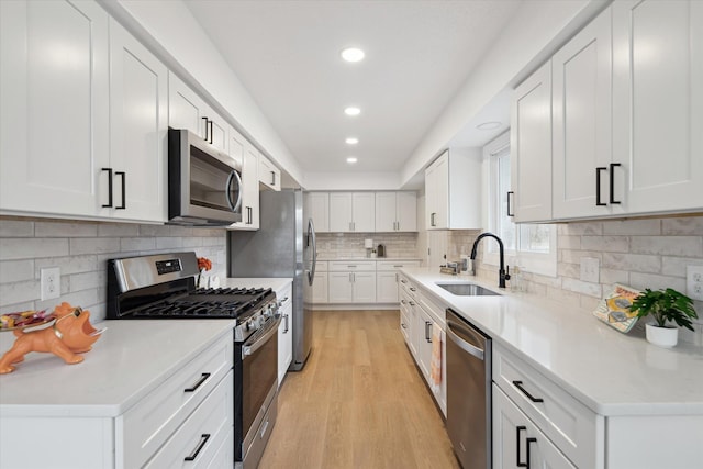 323 13th St, Plainwell, MI 49080 - kitchen with tasteful backsplash, white cabinets, light wood-style floors, appliances with stainless steel finishes, and a sink