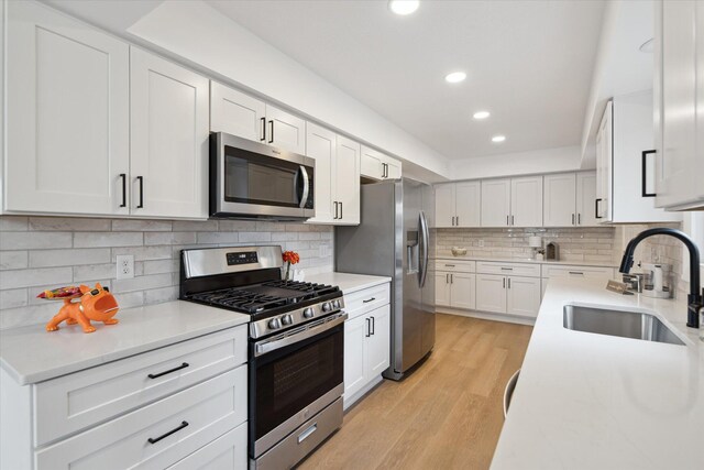 323 13th St, Plainwell, MI 49080 - kitchen featuring a sink, light countertops, appliances with stainless steel finishes, white cabinetry, and light wood-style flooring