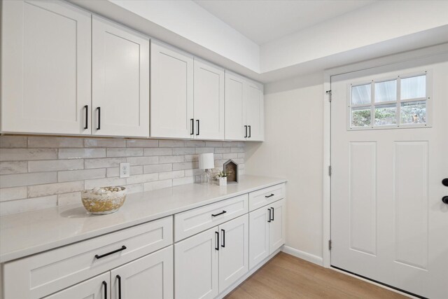 323 13th St, Plainwell, MI 49080 - kitchen with white cabinetry, backsplash, light countertops, and light wood-type flooring