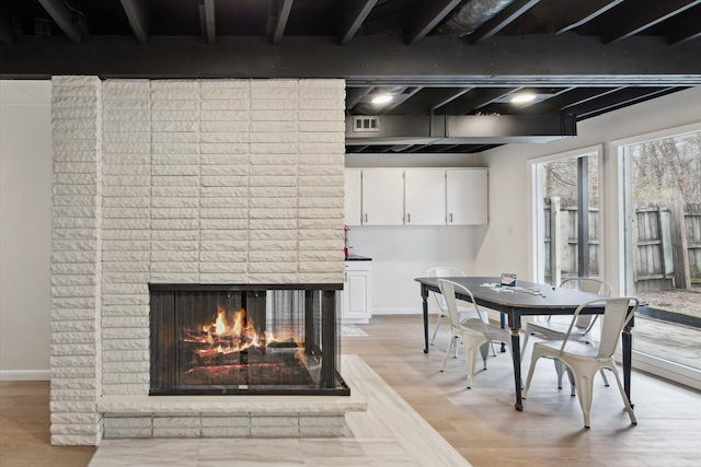 323 13th St, Plainwell, MI 49080 - dining room featuring light wood-style flooring, baseboards, visible vents, and a brick fireplace