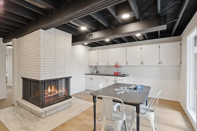 323 13th St, Plainwell, MI 49080 - kitchen with a sink, visible vents, white cabinets, and light wood-style floors