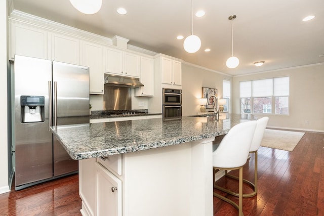 kitchen with a sink, ornamental molding, appliances with stainless steel finishes, a kitchen island with sink, and under cabinet range hood