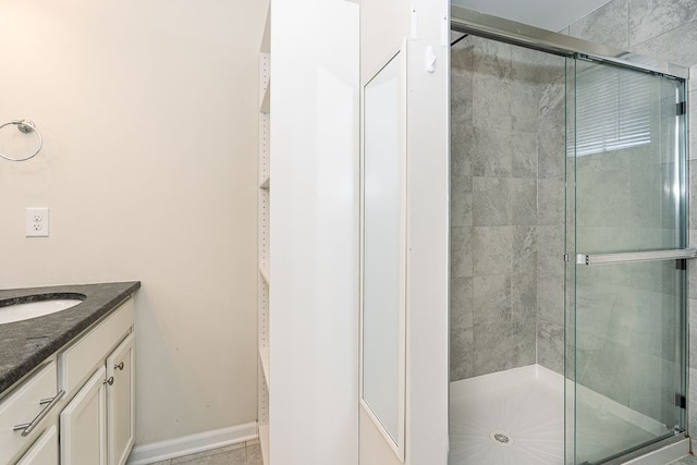 full bath with a shower stall, vanity, and baseboards