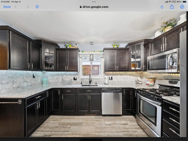 27908 Ryan Rd, Warren, MI 48092 - kitchen featuring appliances with stainless steel finishes, a sink, decorative backsplash, light stone countertops, and glass insert cabinets