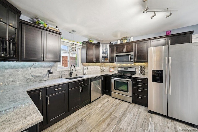27908 Ryan Rd, Warren, MI 48092 - kitchen featuring appliances with stainless steel finishes, tasteful backsplash, wood finish floors, light stone countertops, and glass insert cabinets