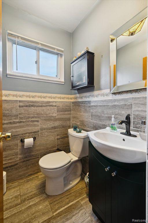 27908 Ryan Rd, Warren, MI 48092 - half bathroom featuring tile walls, vanity, and a wainscoted wall