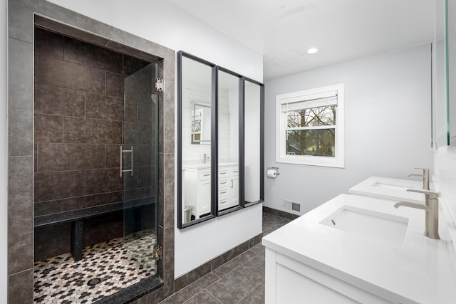 bathroom with a shower stall, a sink, and visible vents