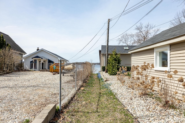 view of home's exterior featuring roof with shingles and fence