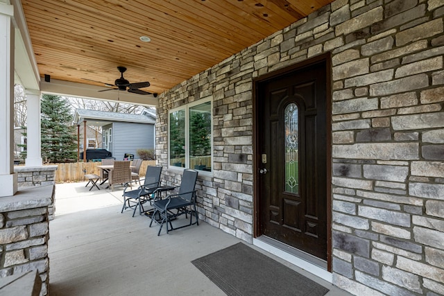 view of exterior entry featuring ceiling fan, stone siding, and outdoor dining area