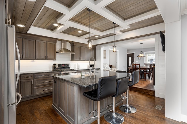 kitchen with stainless steel gas stove, wall chimney exhaust hood, freestanding refrigerator, and coffered ceiling