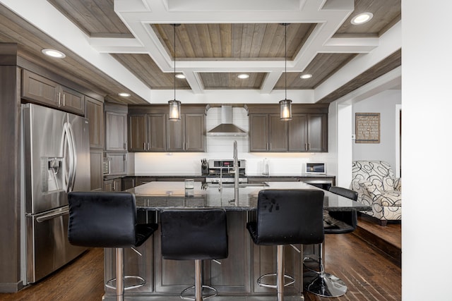 kitchen with wall chimney exhaust hood, dark wood-style flooring, appliances with stainless steel finishes, a kitchen bar, and coffered ceiling