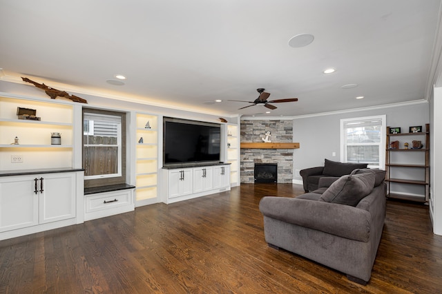 living area featuring a stone fireplace, ornamental molding, recessed lighting, a ceiling fan, and dark wood-type flooring