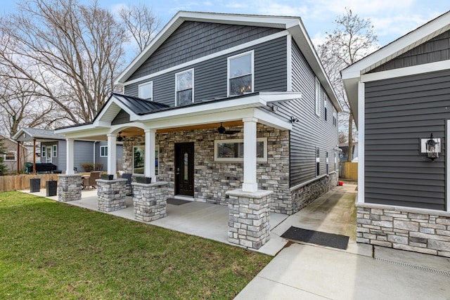 exterior space featuring metal roof, stone siding, a lawn, and ceiling fan
