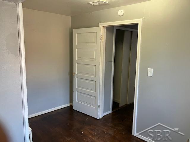 unfurnished bedroom featuring visible vents, baseboards, and dark wood finished floors