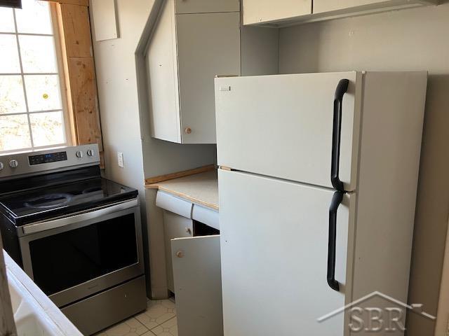kitchen featuring light countertops, freestanding refrigerator, stainless steel electric stove, and white cabinets