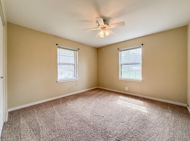 carpeted empty room featuring baseboards, a ceiling fan, and a healthy amount of sunlight