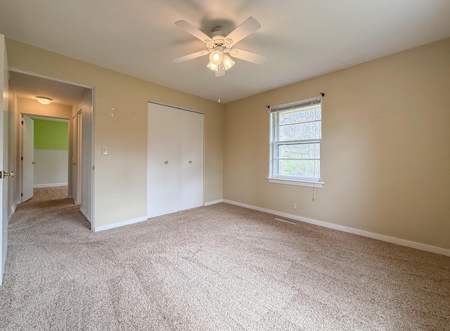 unfurnished bedroom with baseboards, light colored carpet, visible vents, and a closet