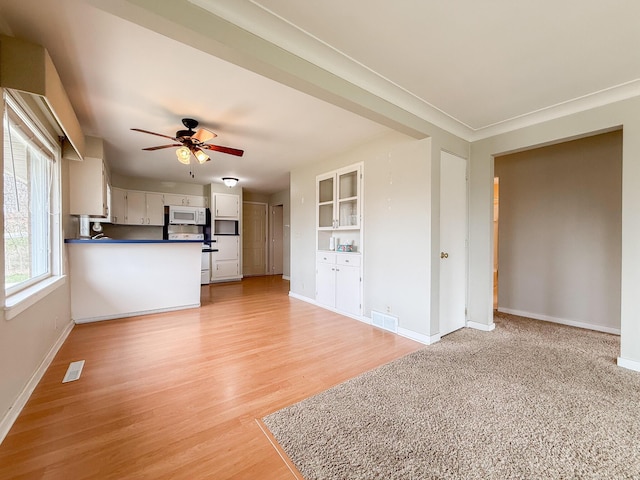 unfurnished living room featuring baseboards, a ceiling fan, light wood-style flooring, and visible vents