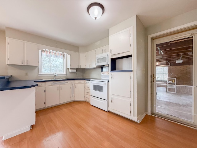kitchen with white appliances, dark countertops, a wealth of natural light, and light wood-type flooring