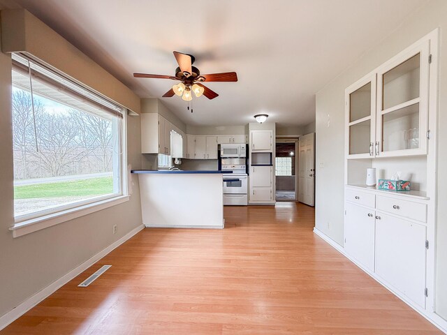 kitchen featuring white appliances, a ceiling fan, a peninsula, light wood-type flooring, and visible vents