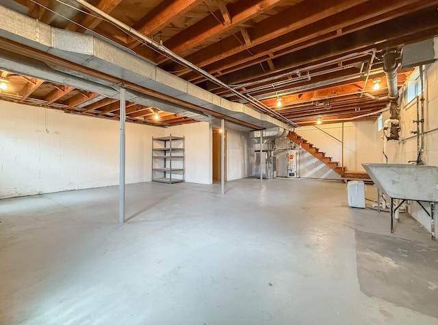 unfinished below grade area with concrete block wall, a sink, and stairway
