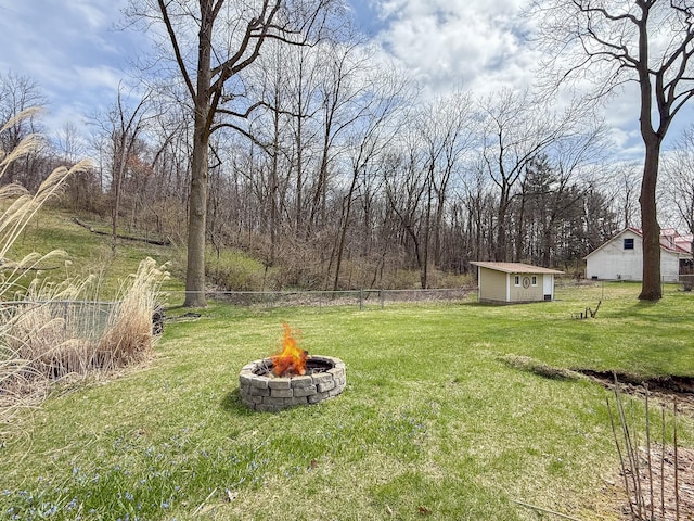 view of yard with fence, a fire pit, an outdoor structure, and a shed