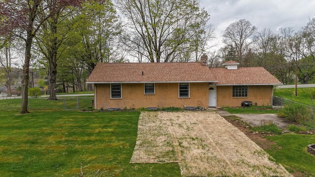 back of house with brick siding, fence, a yard, and a chimney