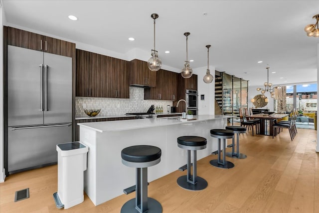 248 Alfred St, Detroit, MI 48201 - kitchen featuring stainless steel appliances, dark brown cabinets, light wood-style flooring, and tasteful backsplash