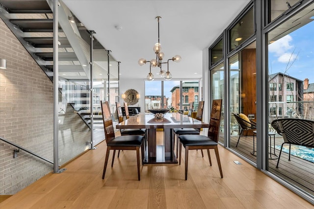 248 Alfred St, Detroit, MI 48201 - dining space featuring light wood finished floors, a notable chandelier, brick wall, and a wall of windows
