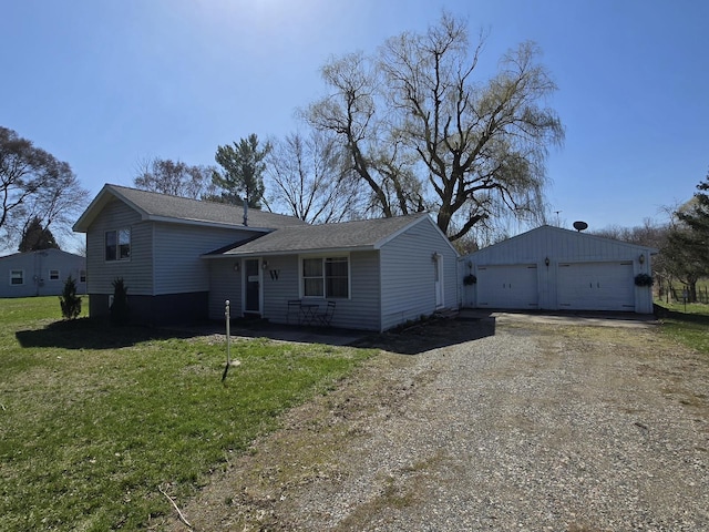 tri-level home with roof with shingles, a detached garage, a front lawn, and an outbuilding