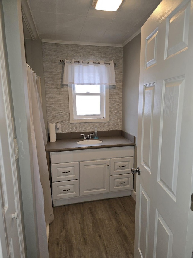 bathroom with crown molding, wood finished floors, and vanity