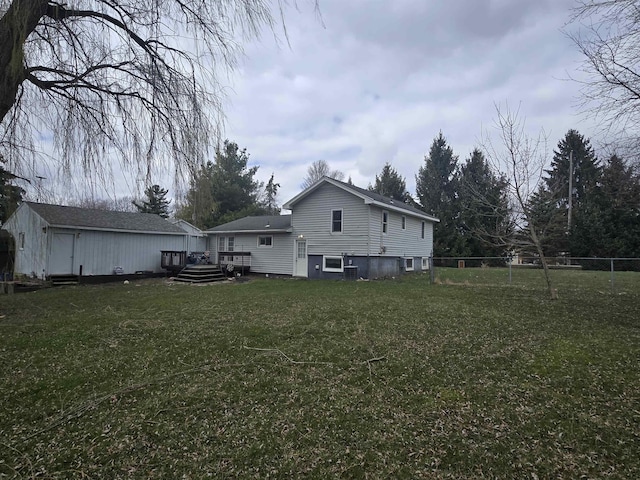 back of property with a lawn, a deck, and fence