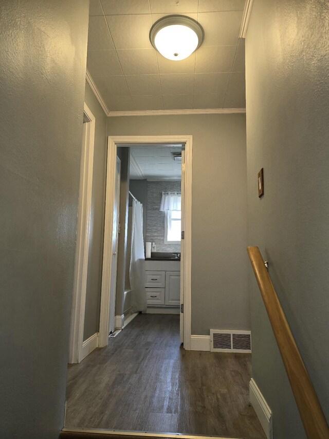 hall featuring visible vents, dark wood-style flooring, baseboards, and ornamental molding