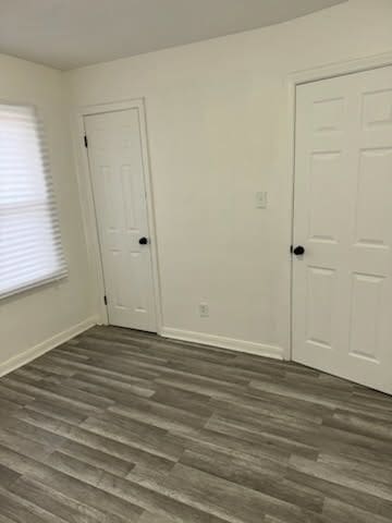 unfurnished room featuring baseboards and dark wood finished floors