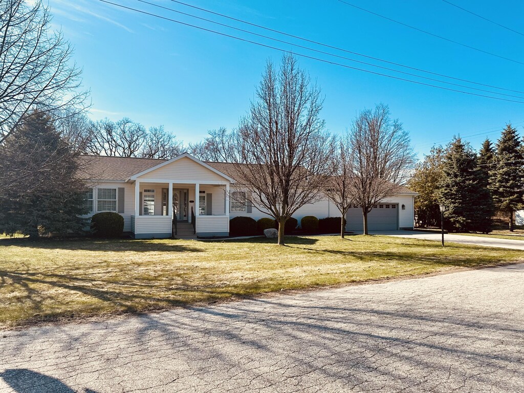 603 Clark St, Ludington, MI 49431 - view of front of home with a front yard, an attached garage, covered porch, driveway, and roof with shingles